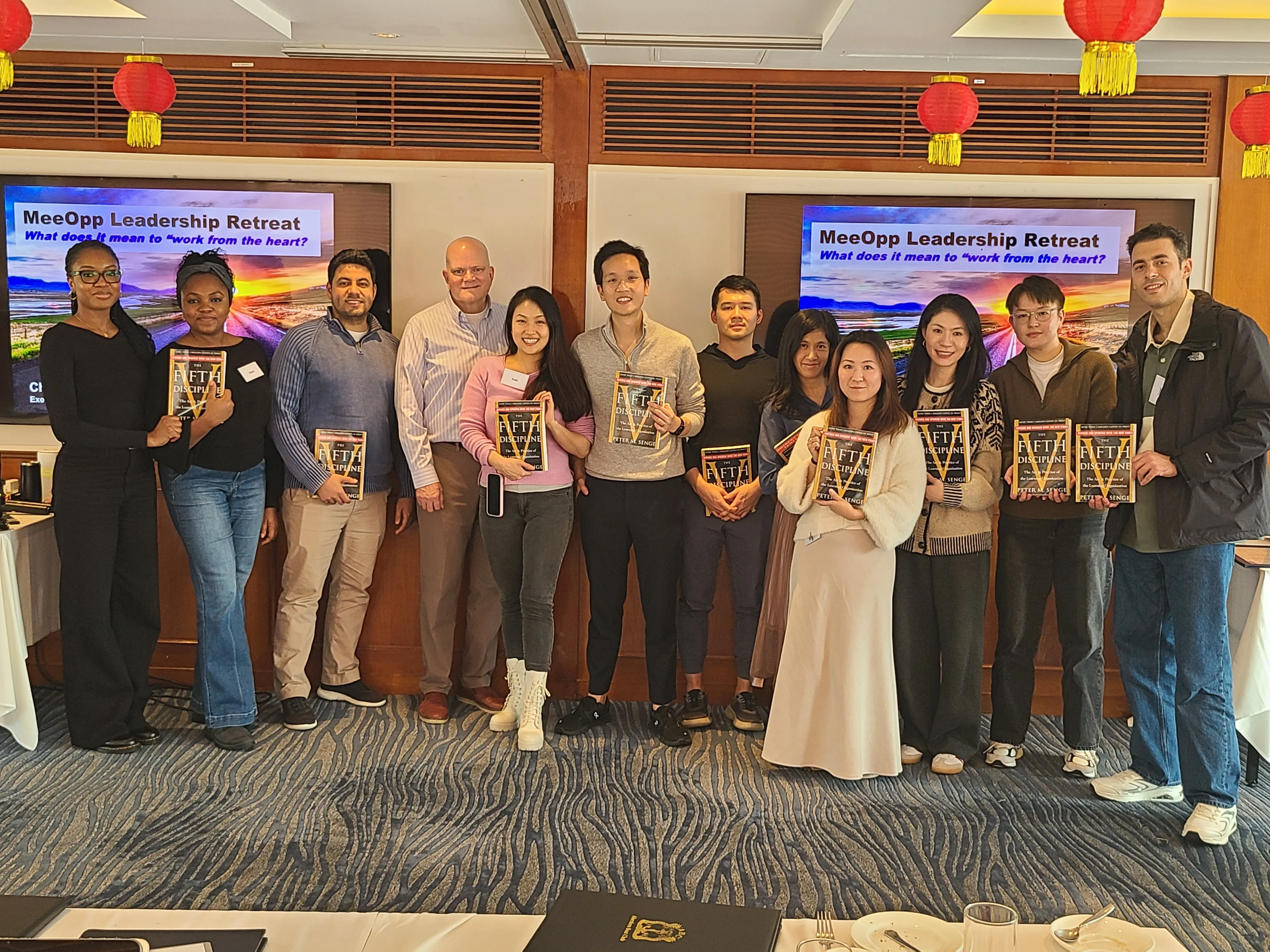 The MeeOpp team at the leadership retreat holding copies of The Fifth Discipline